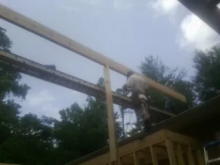 Carpenter setting a ridge beam over a new addition frame — Ice Dam Removal by Roofing Brothers in Pacific Junction