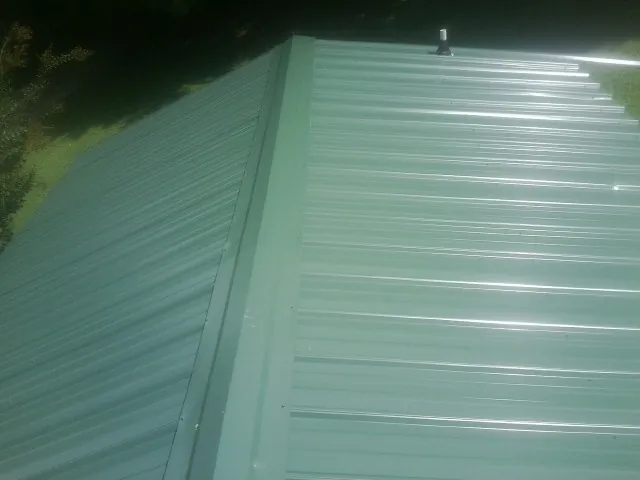 New green metal panels meeting at the ridge of a roof — Flat Roof Repair work by our crew in Pacific Junction