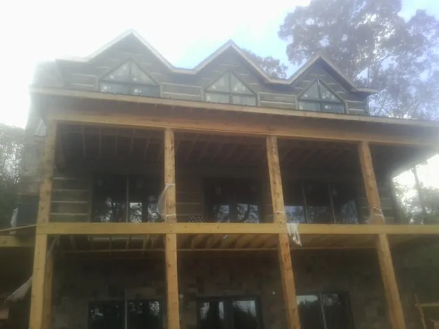Dormers and porch framing on a large log home under construction — Roof Coating work by our crew in Pacific Junction