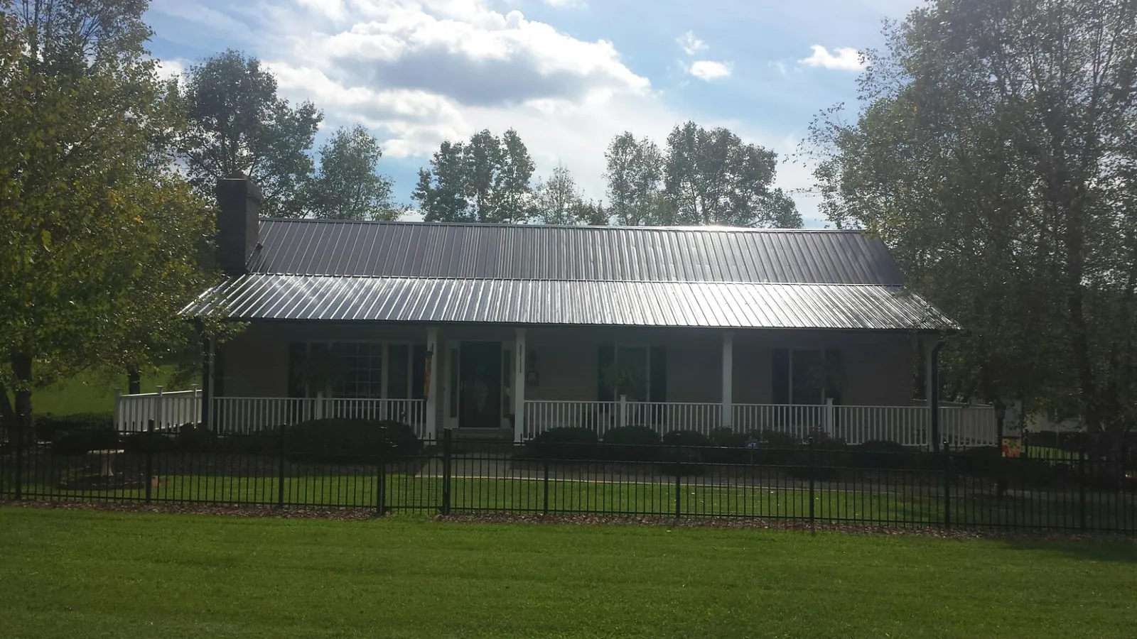 Gray metal roof on a brick ranch with a full width front porch — Gutter Guard Installation work by our crew in Pacific Junction