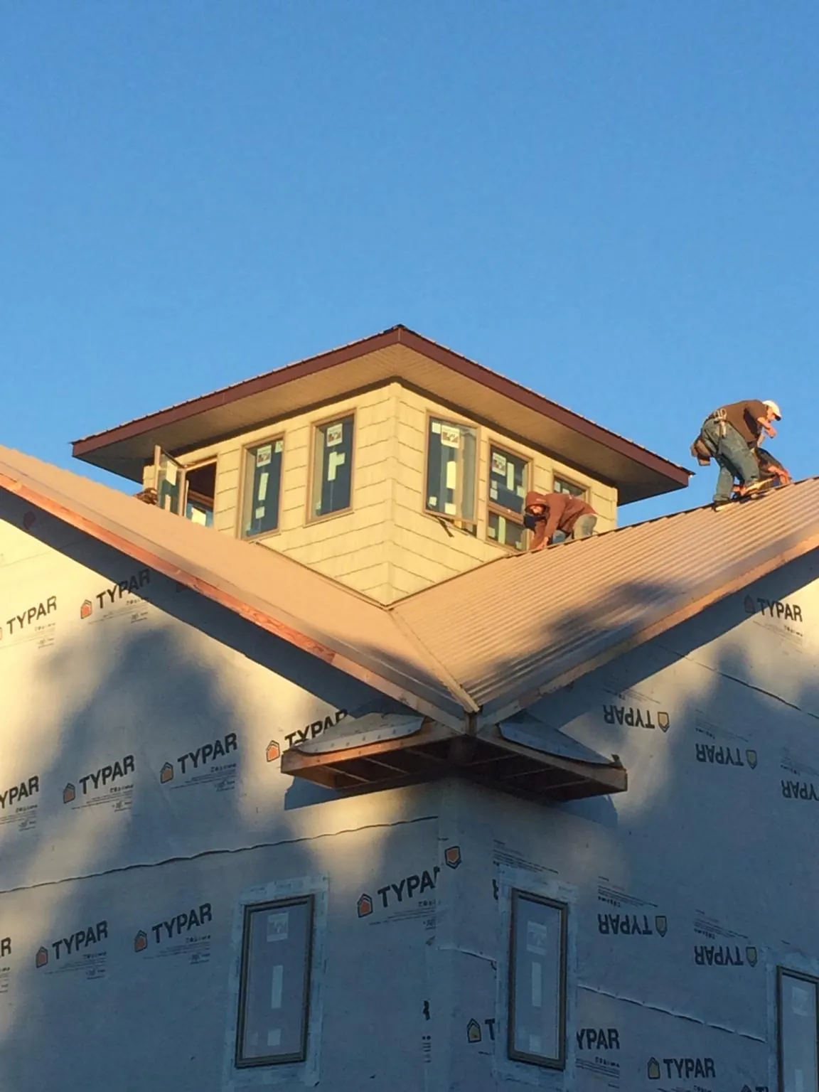 Roofers working around a rooftop cupola on a new metal roof at sunset — Roof Waterproofing in Pacific Junction by Roofing Brothers